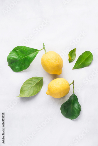 Ripe fresh lemons with green leaves on white background. Organic citrus fruits. Healthy food concept