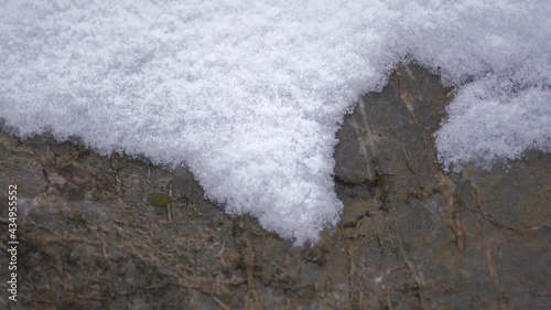 Snow layers accumulating on rock in hard stormy cold weather in winter.Falling stone storm sastrugi mountain snows ice iced surface icy frozen wind windy winds nature white first frost mountain plain. photo