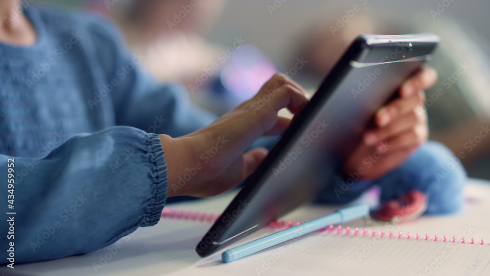Student hand using digital tablet. Girl doing class work on tablet computer Student hand using digital tablet. Girl doing class work on tablet computer