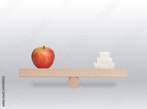 wood scales with red apple and white sugar on the gray background 