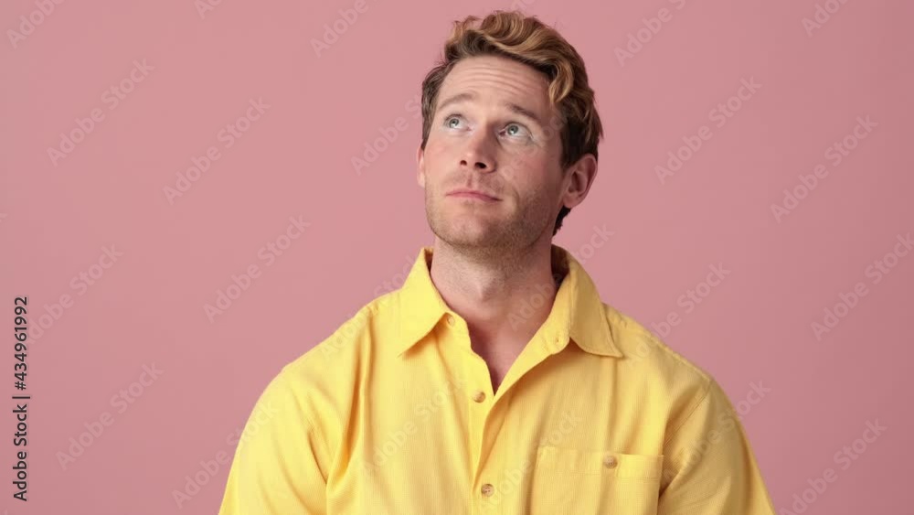 A tired man with makeup looking up and standing in a pink studio A tired man with makeup looking up and standing in a pink studio