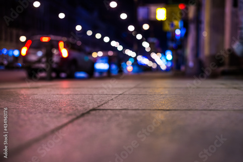 Nights lights of the big city, the car parked at roadside. Close up view from the level of the sidewalk