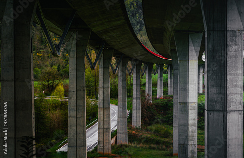 Under a long bridge of concrete columns  between mountains  trees and nature
