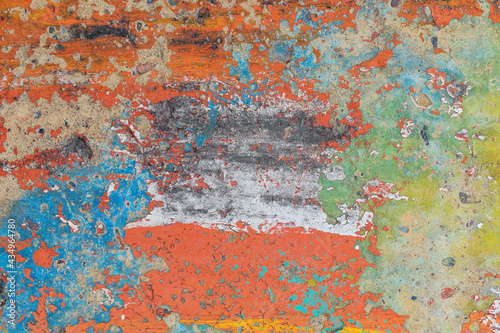 Concrete wall with the remains of old colored paint. Peeling, weathering. Colors - red, blue, white, green.
