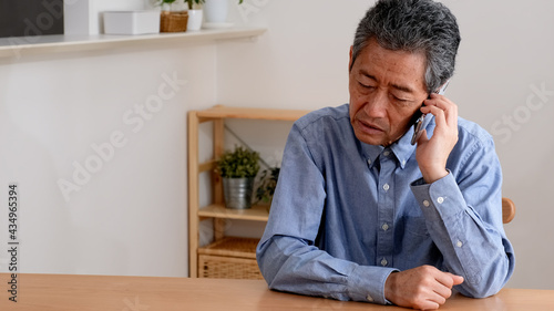 通話をしながら困り果てるシニア男性