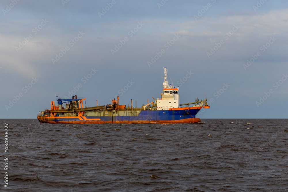 Hopper dredger at sea. Vessel engaged in dredging. Construction Marine offshore works. Dam building, crane, barge, dredger. Hopper dredger at sea. Vessel engaged in dredging. Construction Marine offshore works. Dam building, crane, barge, dredger.