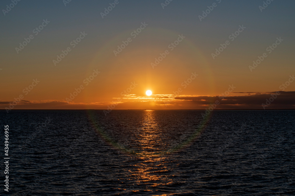 Naklejka premium Beautiful sunset on sky with clouds at sea. Golden hour lighting.
