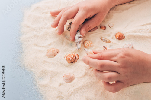 Boy playing with sea shells and sand - Montessori education concept. Fine motoric skills or attention training exercises. Educational toys, cognitive and motor development, selective focus photo