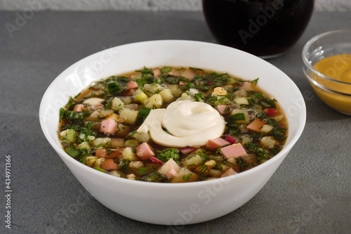 plate of cold okroshka soup with kvass on a gray concrete background close up