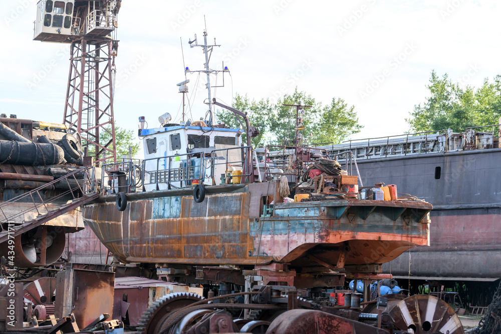 Small vessel ashore on ship repairing yard. Summer time.