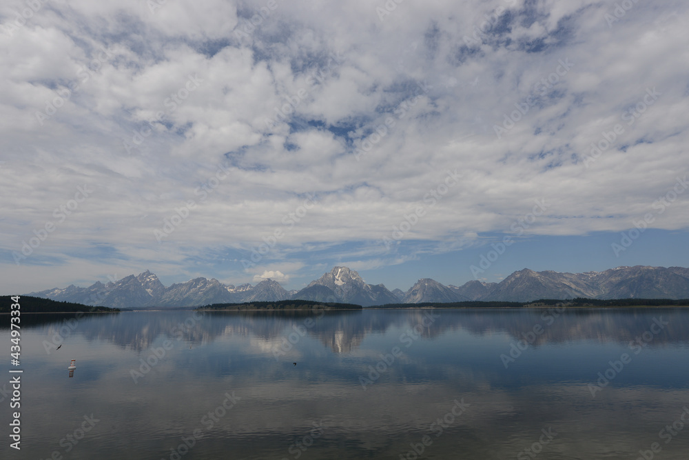 Scenic view of a lake with mountains in the background and lake reflections in Grand Teton National Park on a cloudy day