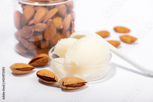 Sweet almond butter and natural almonds on white background.