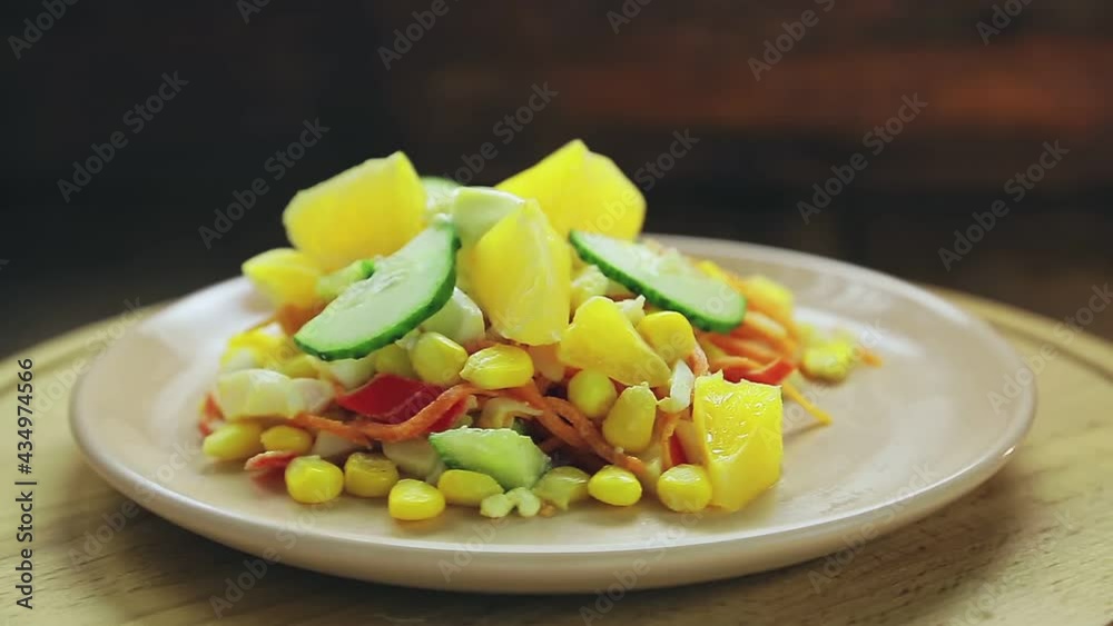 Salad with crab meat decorated with cucumber and orange in a plate on a black background rotates in a circle. Salad with crab meat decorated with cucumber and orange in a plate on a black background rotates in a circle.