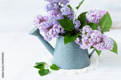 Beautiful fresh violet lilac bouquet in metal watering. Template for gardening, spring time. Greeting card for Saint Valentine's Day, 8 march, Women's day, Mother's day. White background, close up