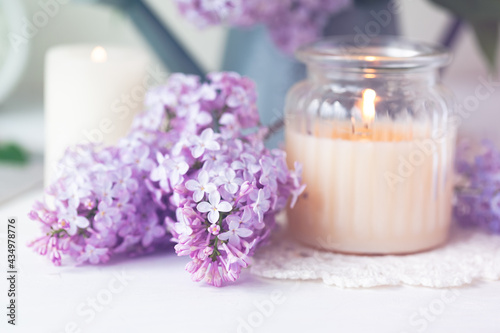 Beautiful composition with fresh violet lilac bouquet in watering and candles. Cozy atmosphere. Greeting card for Saint Valentine's Day, 8 march, Women's day, Mother's day. White background