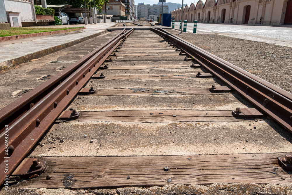 Abandoned and rusty train tracks between the buildings of a city. Abandoned and rusty train tracks between the buildings of a city.