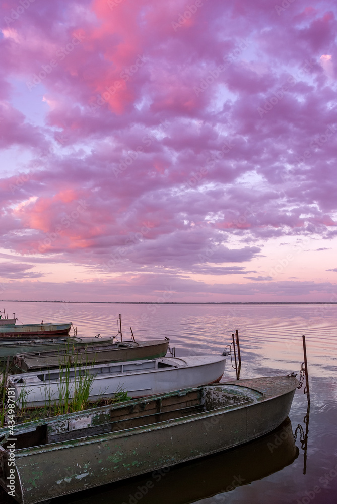 Beautiful landscape with boats on the lake and clouds in the sunset sky.