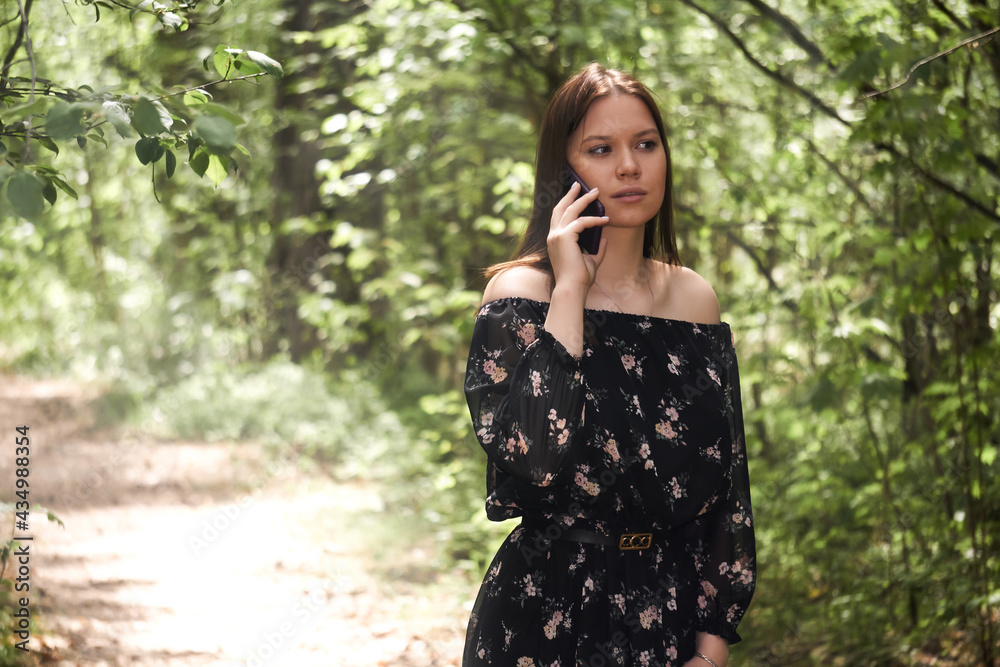 beautiful girl talking on the phone walking in the sunny forest park beautiful girl talking on the phone walking in the sunny forest park