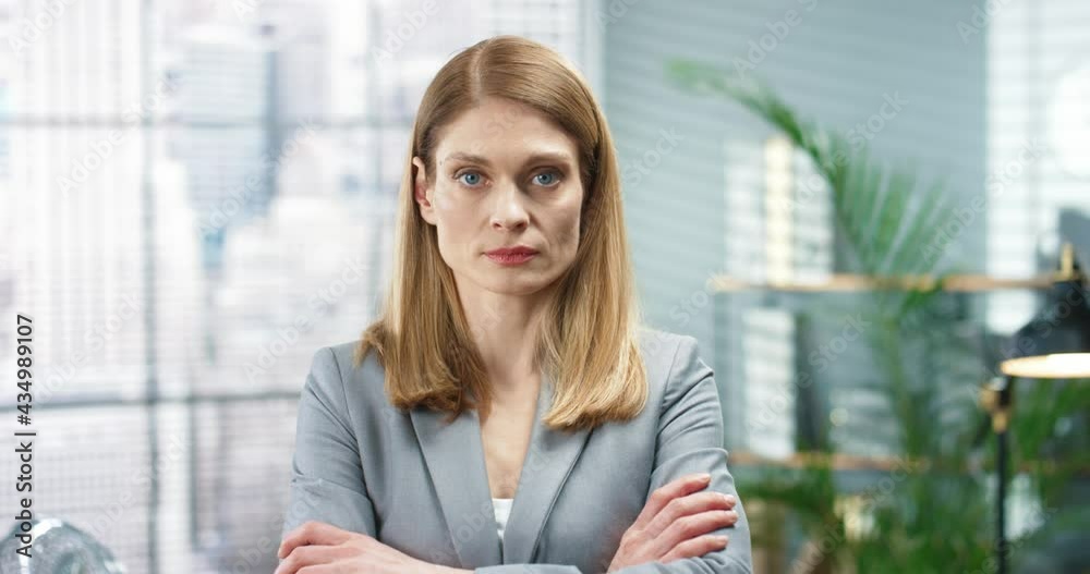 Young beautiful female office worker looking at camera with serious face expression. Close up portrait, Caucasian professional woman employee in cabinet at work, businesswoman concept Young beautiful female office worker looking at camera with serious face expression. Close up portrait, Caucasian professional woman employee in cabinet at work, businesswoman concept
