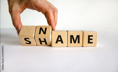 Name or shame symbol. Businessman turns wooden cubes and changes the word 'shame' to 'name' or vice versa. Beautiful white background, copy space. Business, name or shame concept.