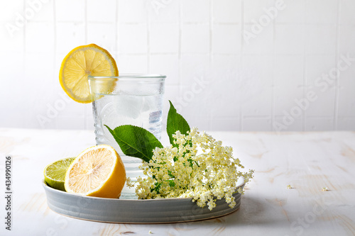 Glass of homemade elderflower lemonade with lemon, lime juice and freshly picked elderberry flowers. Healthy refreshing  mocktail with elderflower cordial syrup