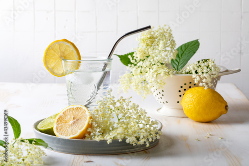 Glass of homemade elderflower lemonade with lemon, lime juice and freshly picked elderberry flowers. Healthy refreshing  mocktail with elderflower cordial syrup