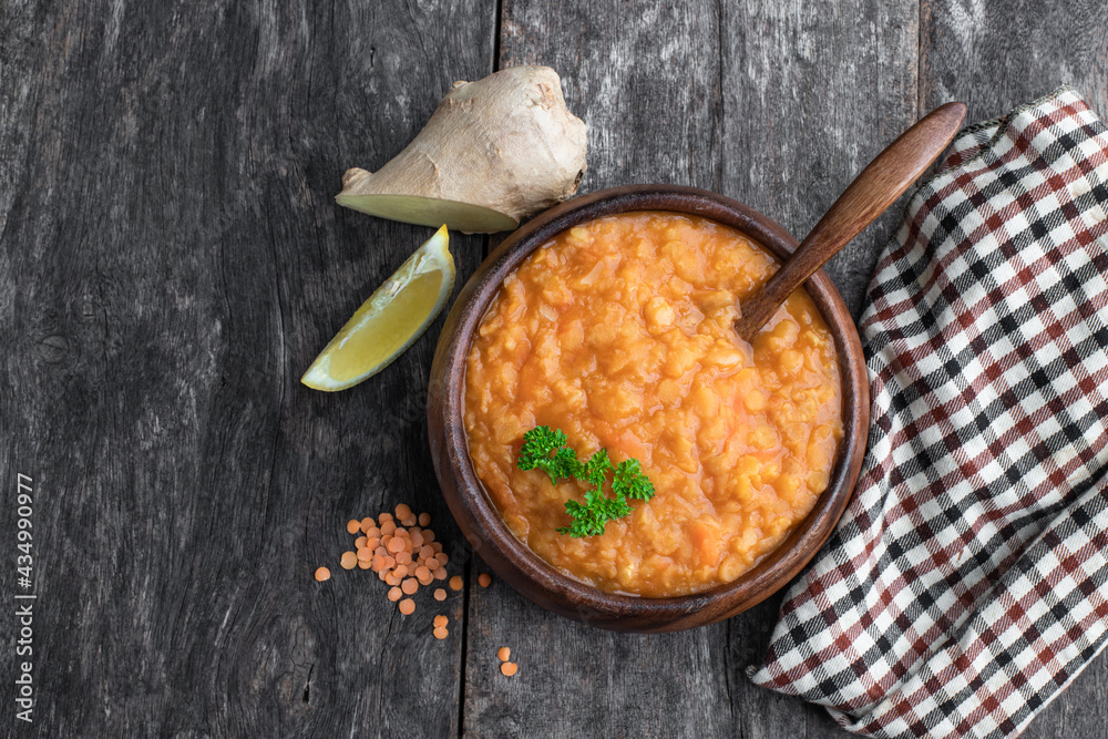 Vegan Red Lentil Soup in wooden bowl on rustic table Vegan Red Lentil Soup in wooden bowl on rustic table