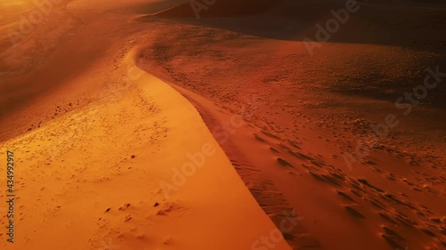 Drone shot from close distance to dazzling sand dune. Aerial view of barren wilderness of wide orange desert. Empty massive sand hills in africa. Magnificent natural landscape under clear blue sky photo