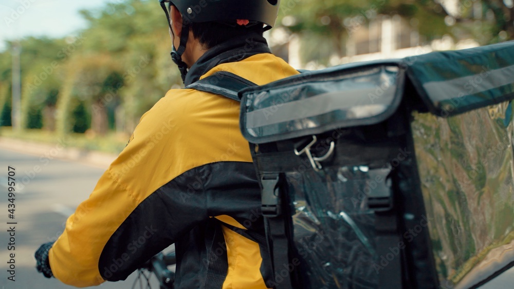 Food Delivery Man Wearing Protective Medical Face Mask and Thermal Backpack Rides a Bike to Deliver Order. Young Asian man working as a food delivery person. He riding a bike for sustainable way. Food Delivery Man Wearing Protective Medical Face Mask and Thermal Backpack Rides a Bike to Deliver Order. Young Asian man working as a food delivery person. He riding a bike for sustainable way.