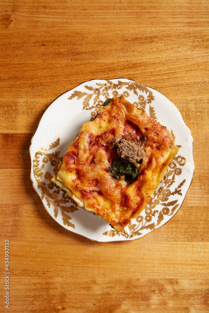 Top view of spinach and mushroom lasagna served on a white plate with gold ornate details Top view of spinach and mushroom lasagna served on a white plate with gold ornate details