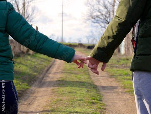 couple in love walking on a dirt road holding each other with their fingers