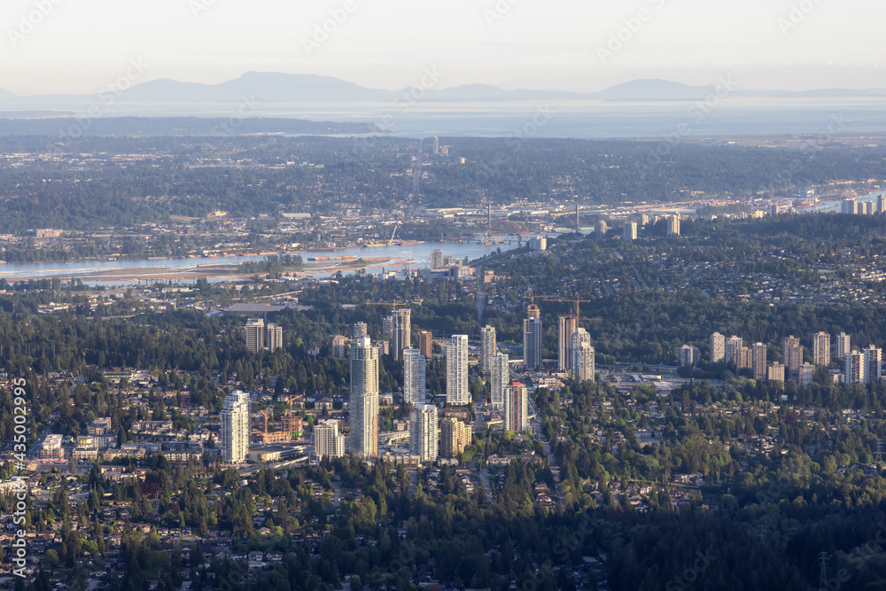 Aerial View from Airplane of Residential Homes and Buildings in a modern city during sunny evening. Taken in Coquitlam, British Columbia, Canada.