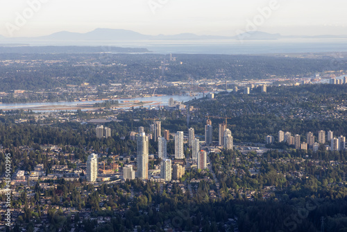 Aerial View from Airplane of Residential Homes and Buildings in a modern city during sunny evening. Taken in Coquitlam, British Columbia, Canada.