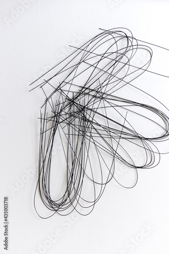multiple crafting wire (painted black) bent and scattered on white - photographed from above in flat lay composition