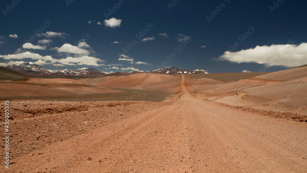 The dirt road high in the Andes mountains. Traveling along the route across the arid desert and mountain range. The sand and death valley under a deep blue sky in La Rioja, Argentina.