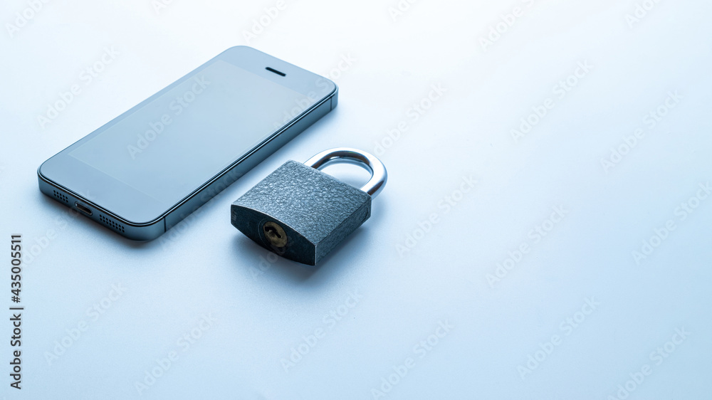Fototapeta premium Business security protection. Modern space grey mobile phone with padlock, key on white background. Smartphone fraud, online scam and cyber security threat.