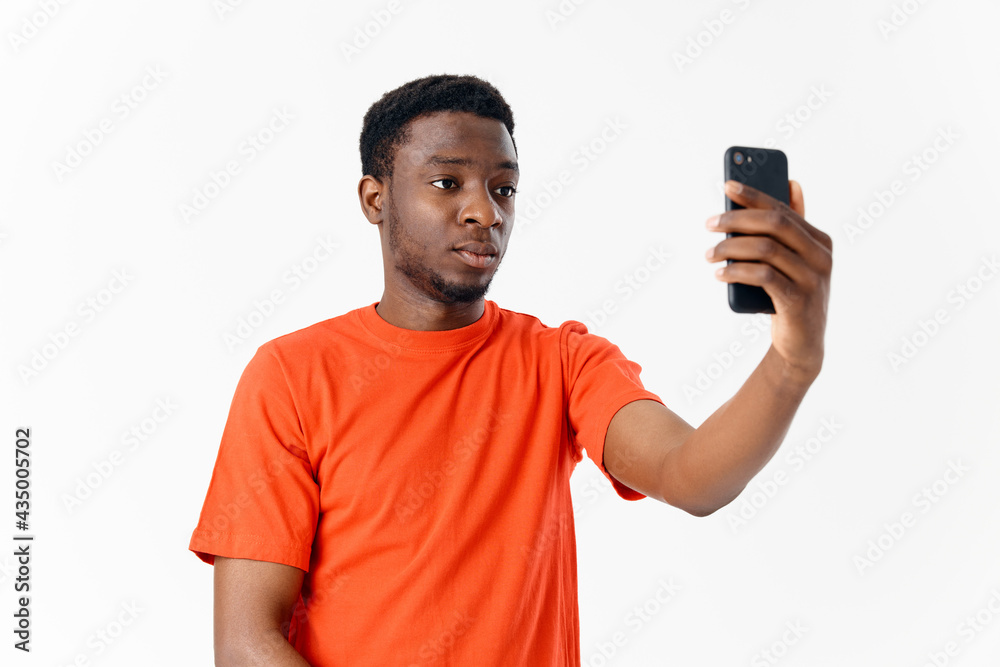 handsome man of african appearance holding a mobile phone in front of his face on a light background handsome man of african appearance holding a mobile phone in front of his face on a light background