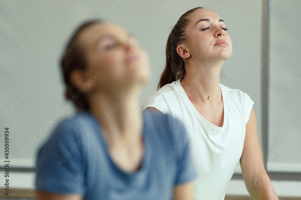 Two Caucasian good shape female Yoga players doing body stretches and practice together. Idea for self healthcare and balance of body and mind Two Caucasian good shape female Yoga players doing body stretches and practice together. Idea for self healthcare and balance of body and mind