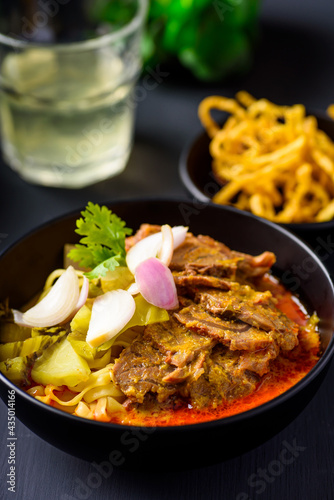 Northern Thai food (Khao soi), Spicy coconut milk curry egg noodles soup with beef in a bowl 