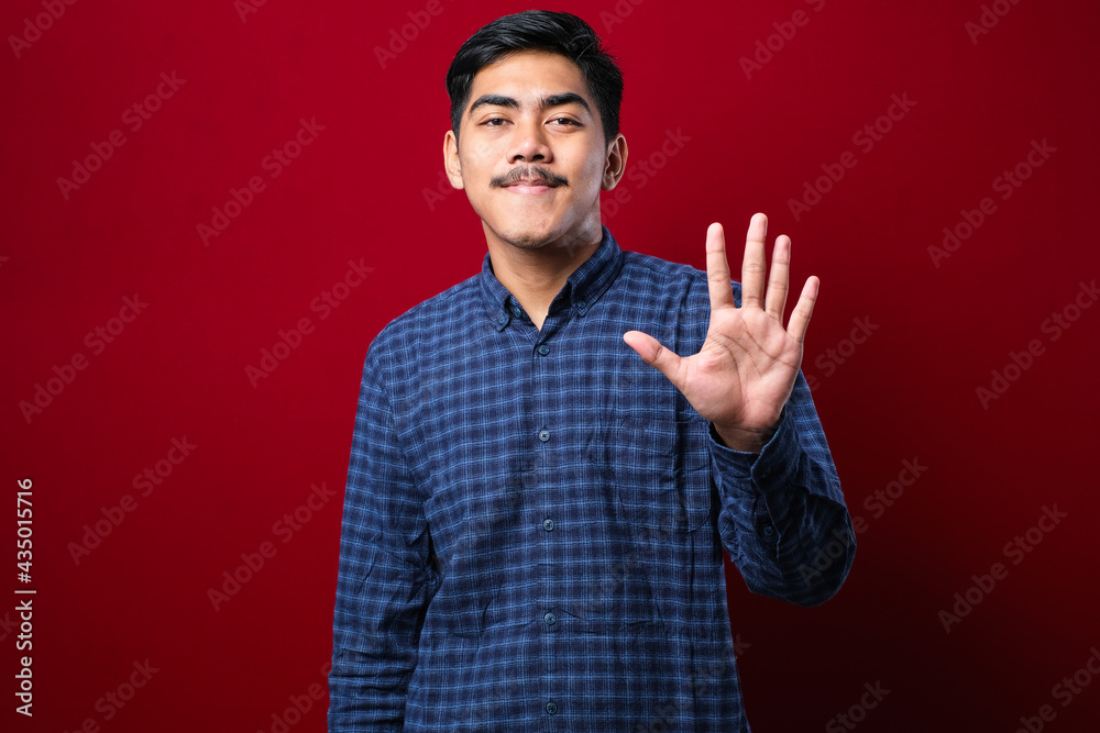 Naklejka premium Handsome young man wearing casual clothes showing and pointing up with fingers number five while smiling confident and happy