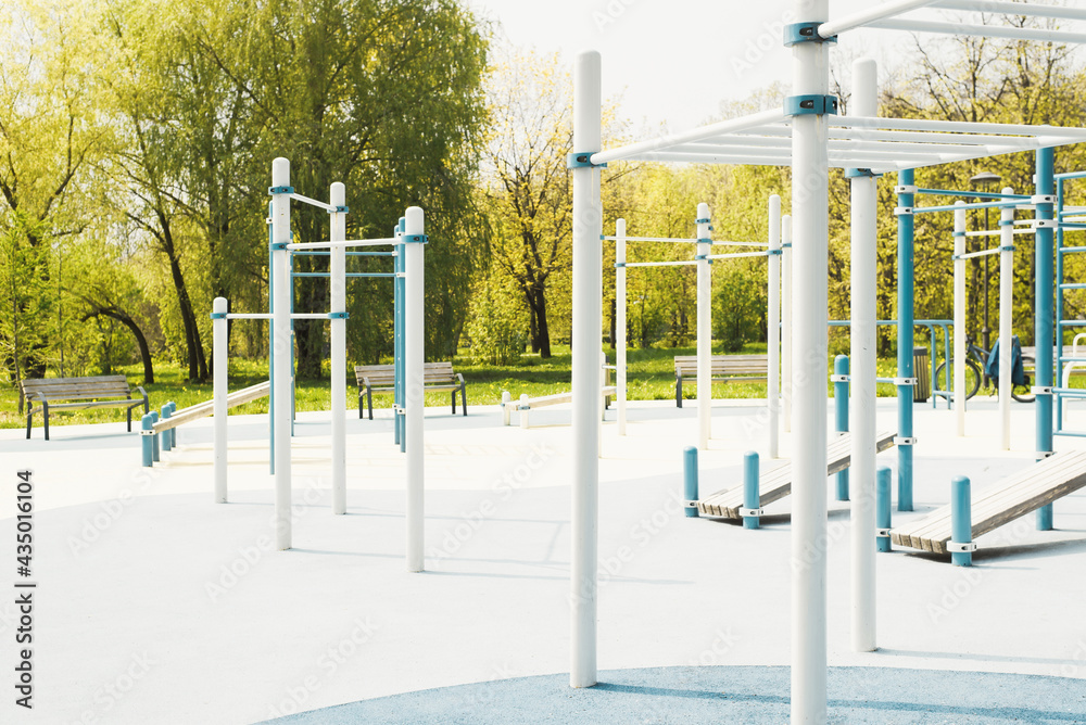 Fototapeta premium Outdoor sports ground. Pull up bars, crossbars, equipment and rubber flooring for training in the park. Summer sunny day. No people