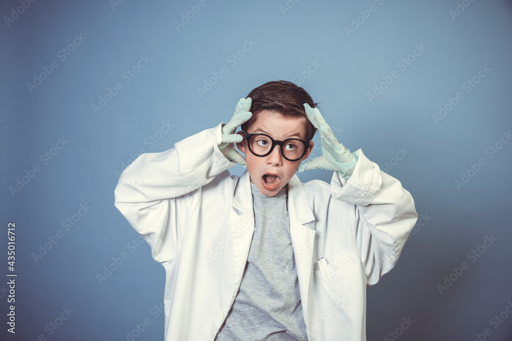 cool school boy with thick black glasses is dressed as mad scientist with white coat in front of blue background cool school boy with thick black glasses is dressed as mad scientist with white coat in front of blue background