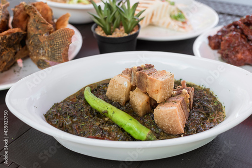 Delicious laing with fried pork belly bits with other Filipino cuisine. Sumptuous lunch or buffet at an al fresco restaurant. photo