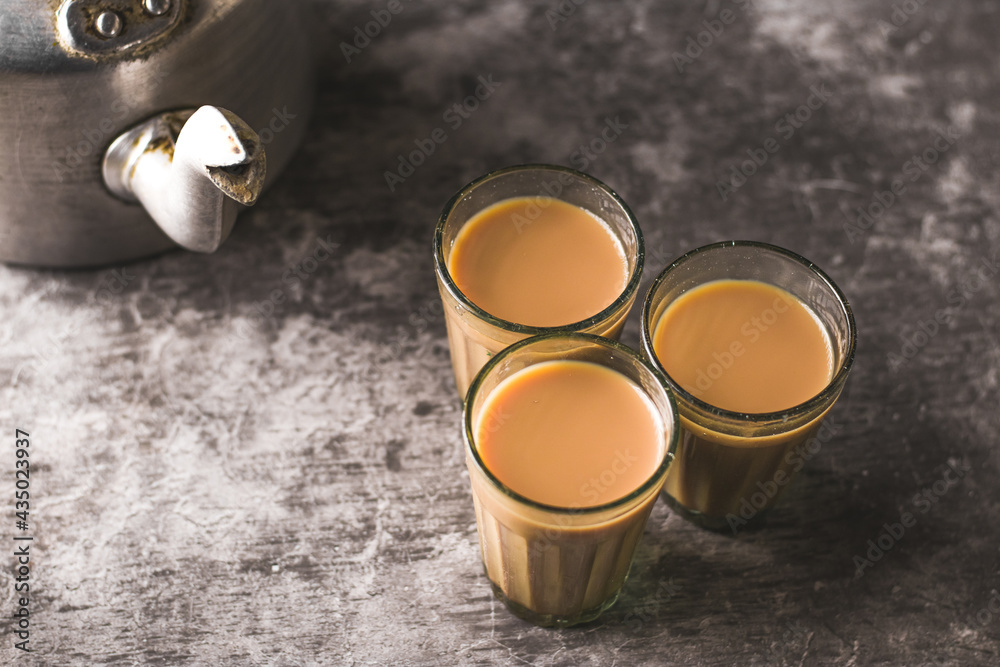 Indian chai in glass cups with metal kettle and other masalas to make the tea.