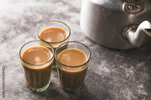 Indian chai in glass cups with metal kettle and other masalas to make the tea.