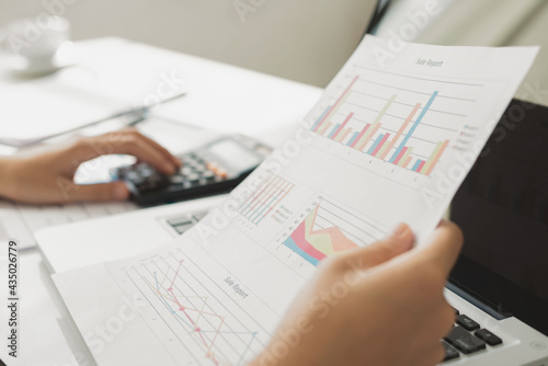 Business woman using calculator and writing make note with calculate. taxes and economic concepts. Savings, finances and economy concept through a laptop.