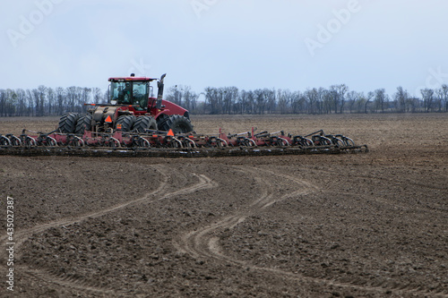 red tractor in a field rear view  tractor with a plow on an agricultural field. big red tractor working in the field  harvesting  business  agriculture. soil preparation  spring season. Ukraine