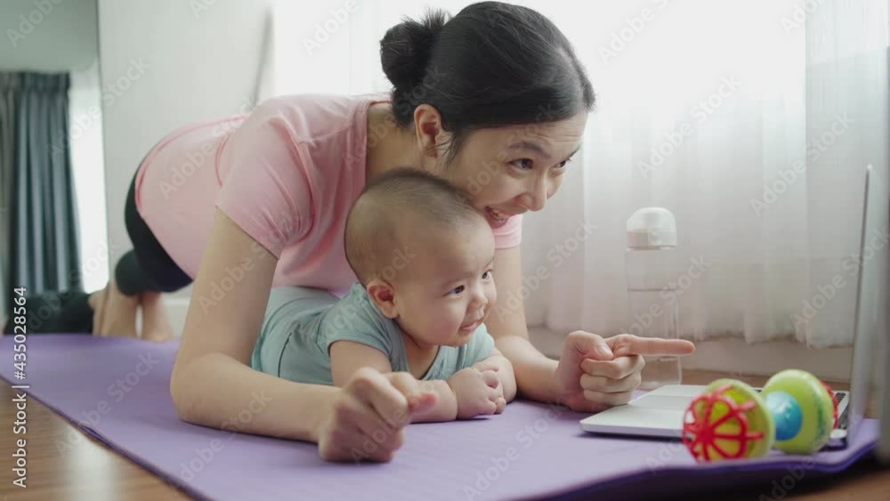 Healthy Asian Mother and her Adorable little baby boy doing yoga plank exercises while having online class on laptop. Healthy Asian Mother and her Adorable little baby boy doing yoga plank exercises while having online class on laptop.