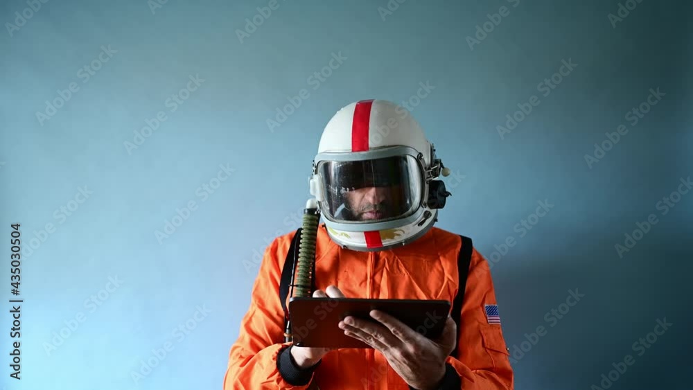 Astronaut with helmet Cosmonaut wearing orange space suit with white helmet and using a tablet Astronaut with helmet Cosmonaut wearing orange space suit with white helmet and using a tablet