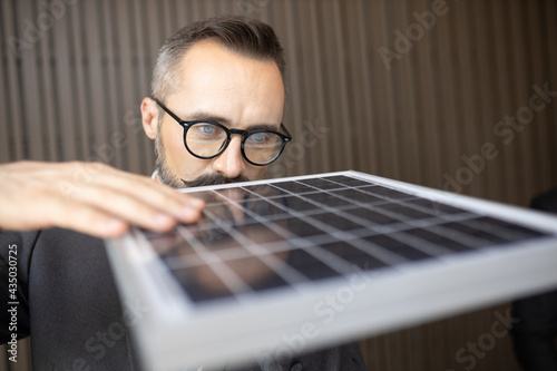man touching and checking photovoltaic panel while working on solar power station on sunny day. Solar energy concept